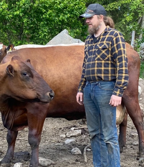 Miika Takkunen. Kuvassa henkilö seisoo lehmän vierellä.